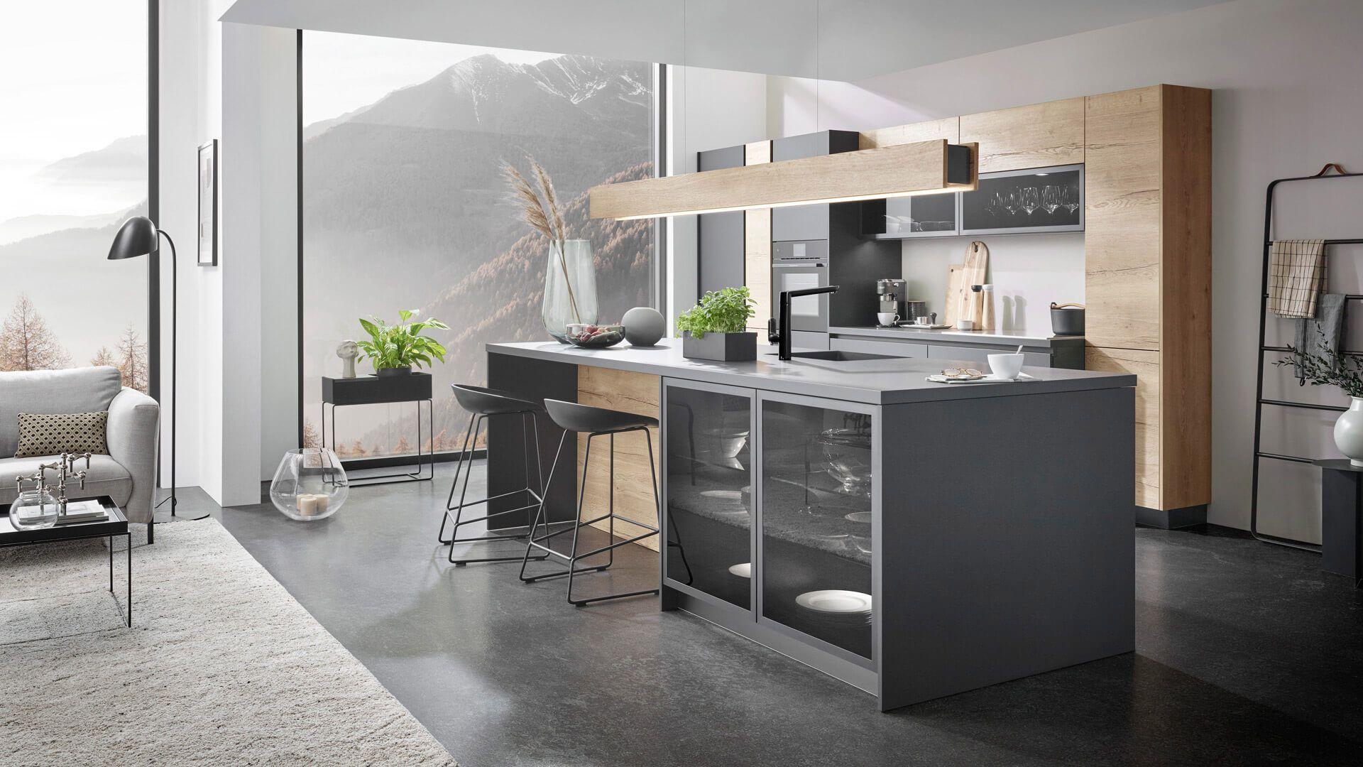 Sachsenküche Einbauküche in Dunkelgrau und Holz mit Kochinsel beim Küchenstudio Borcherts Berlin. Minimalistisches Küchendesign, grifflose Fronten und eine hängende LED-Leuchte in Holz-Optik.